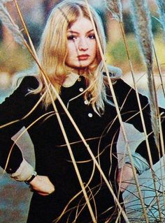 a woman standing in tall grass with her hands on her hips