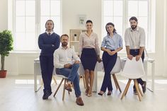 five people are sitting at a table in the middle of a room with white walls