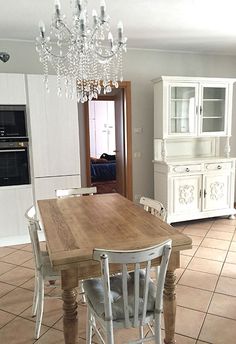 a dining room table with chairs and a chandelier hanging from it's ceiling