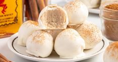 cinnamon buns are stacked on a plate next to cinnamon sticks and jars filled with powdered sugar