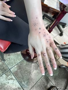 a woman's hand with stars and moon tattoos on it, sitting next to a red chair