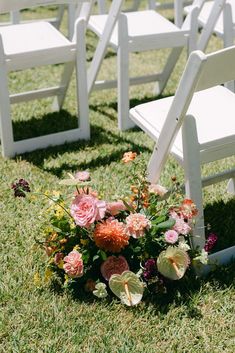 white chairs with flowers on them sitting in the grass at a wedding or other event