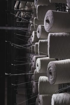 many rolls of yarn are hanging on a rack in a room that is black and white