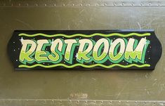 a sign that says rest room on the side of a metal structure with green and black lettering