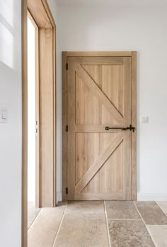 an open wooden door in a room with tile flooring and white walls on either side