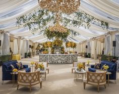 a room with couches, tables and chandeliers on the ceiling is decorated with white drapes