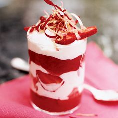 a red and white dessert with strawberries on top is sitting on a pink cloth