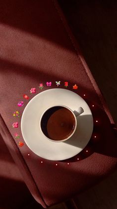 a cup of coffee sitting on top of a white saucer next to a red cloth