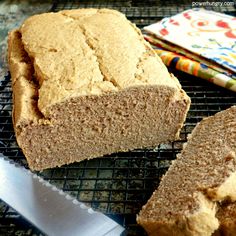 a loaf of bread sitting on top of a cooling rack next to a knife and napkin