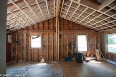 an unfinished room with wood framing and windows