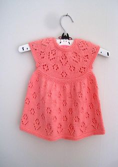 a pink crocheted dress hanging on a clothesline with a white hanger