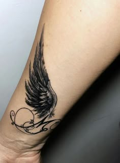 a woman's arm with a tattoo on it and an angel wing in the middle