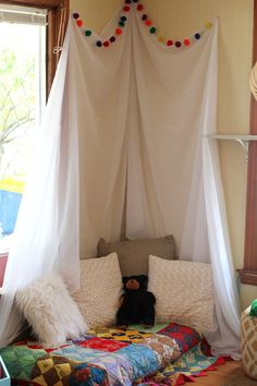 a bed with white curtains and pillows on top of it