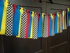 a bunch of colorful ribbons hanging from the side of a wooden door with black and white checkerboard on it