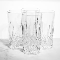 three clear glass tumblers sitting on top of a marble countertop next to each other