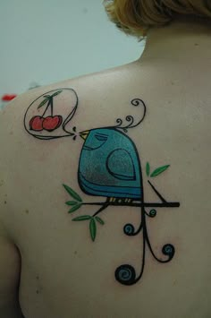 the back of a woman's shoulder with a bird and cherry tattoo on it