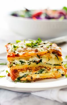 two pieces of lasagna stacked on top of each other with vegetables in the background