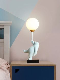 an elephant lamp is on top of a nightstand next to a night stand with a bed in the background