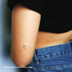 a small tattoo on the back of a woman's left arm, with an arrow