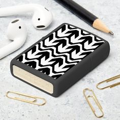 black and white pattern with gold accents on an apple airpods case next to earbuds