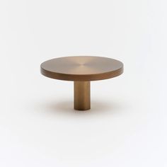 a round wooden table on a white background with an object in the foreground that appears to be metal