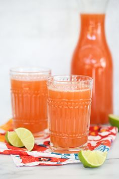 two glasses filled with orange juice and limes