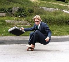 a man riding a skateboard down the middle of a street holding a briefcase in his hand