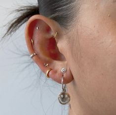 a close up of a person wearing ear piercings and an earring on their left side