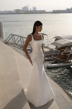 a woman in a white dress standing by the water