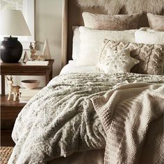 a bed with white blankets and pillows in a bedroom next to a lamp on a table