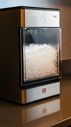 a silver and black toaster oven sitting on top of a counter next to a glass container filled with ice