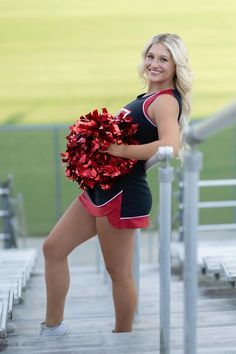 a cheerleader holding a pom - pom while standing on the sidelines