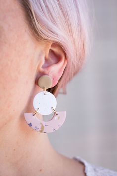 a close up of a person wearing some kind of earring with pink hair and white shirt