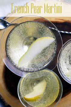 three glasses filled with liquid sitting on top of a wooden table next to spoons