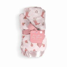 a pink and white baby blanket with cowboy boots on it's side, tied up to a tag