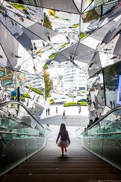 a woman is walking down an escalator with many mirrors on the ceiling above her