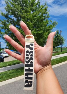 a person holding up a lanyard with the word jesus on it in front of some trees