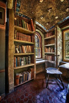 a room with bookshelves and a chair in front of a window filled with lots of books