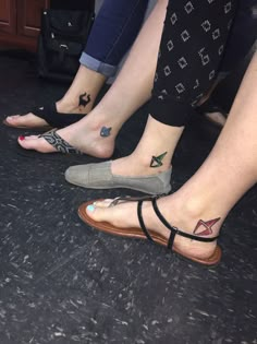 three people with tattoos on their feet sitting next to each other