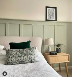 a white bed topped with pillows next to a night stand