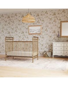 a baby crib and dresser in a room with floral wallpaper on the walls