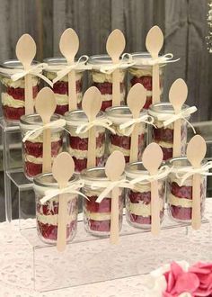 there are many desserts in jars on the table with wooden spoons and forks