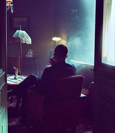 a man sitting in a chair looking out the window