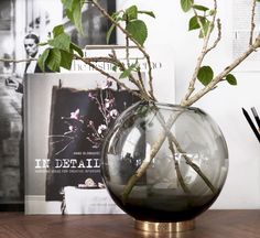 a vase with branches in it sitting on a table next to some books and pictures