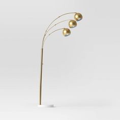 three golden balls are on the top of this floor lamp, and it's base is