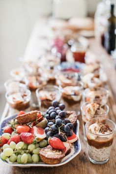 a wooden table topped with plates and cups filled with desserts next to each other