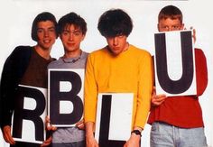 four young men holding up letters that spell out the word b u