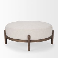 a round ottoman sitting on top of a white floor next to a wooden frame and foot rest