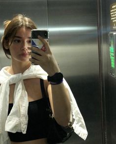 a woman taking a selfie in front of an elevator door with her cell phone