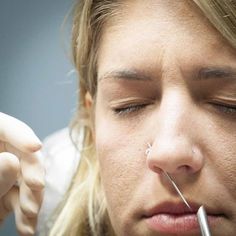 a close up of a person with an electronic device in their mouth and nose piercings